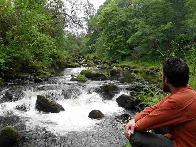 photo of a man sitting near a little waterfall on the Deveron near Beldorney